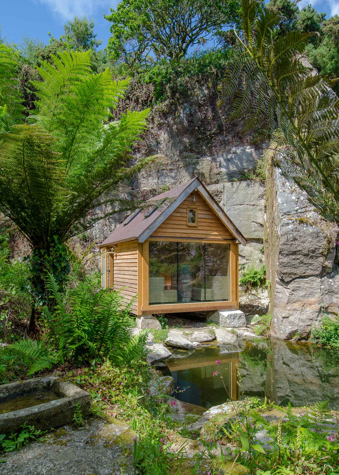 oak timber framed sauna cabin with larch cladding and copper fish scale tiles in a granite quarry on the waters edge